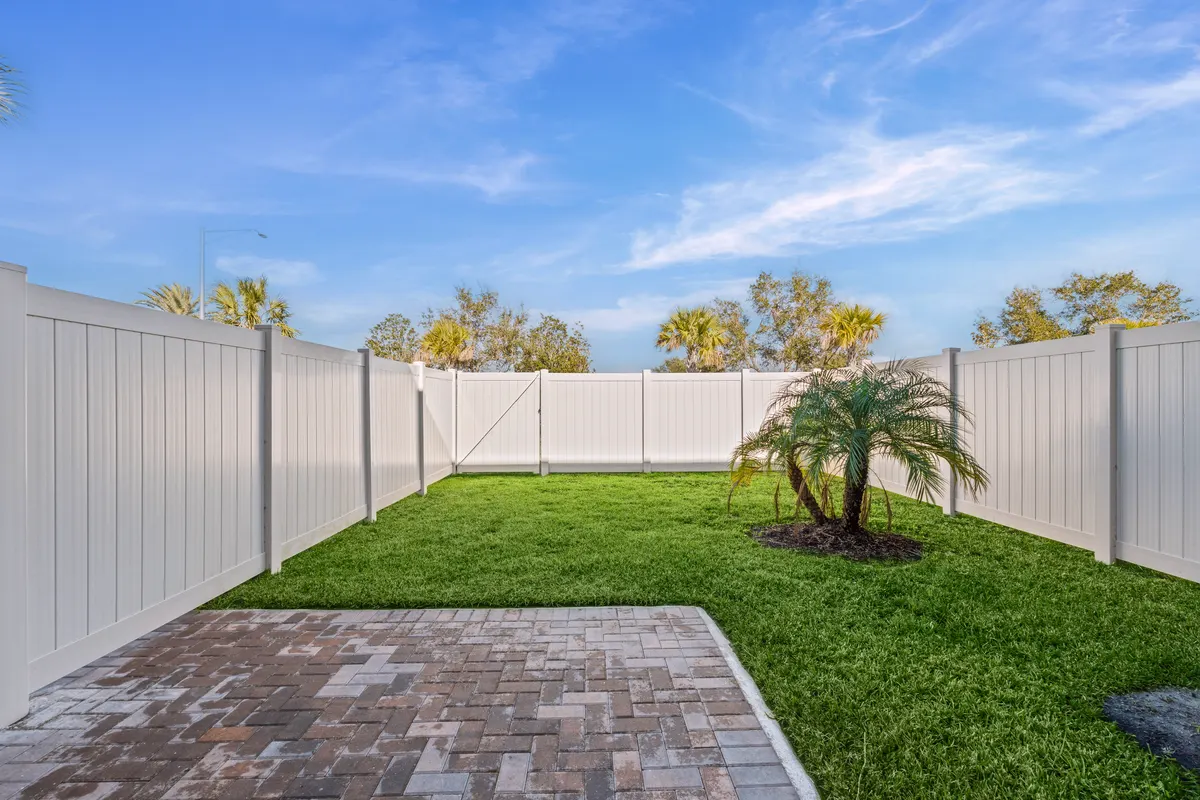 Fenced-in backyard with a lawn, a paver patio and a young palm