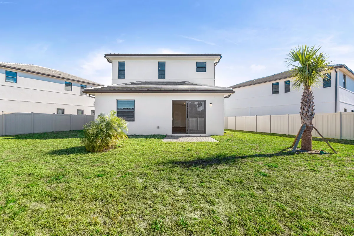 Rear elevation with a fenced lawn and a palm