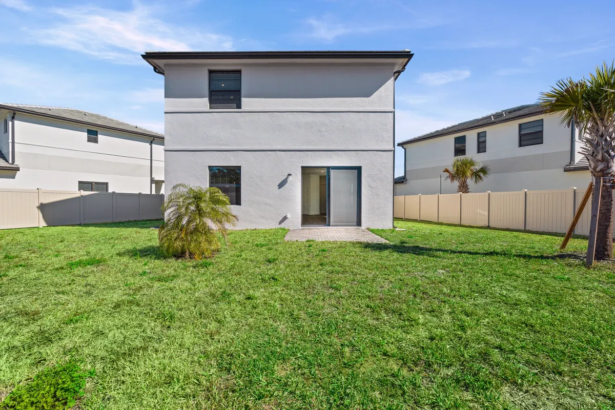 Rear elevation with a fenced lawn and a palm
