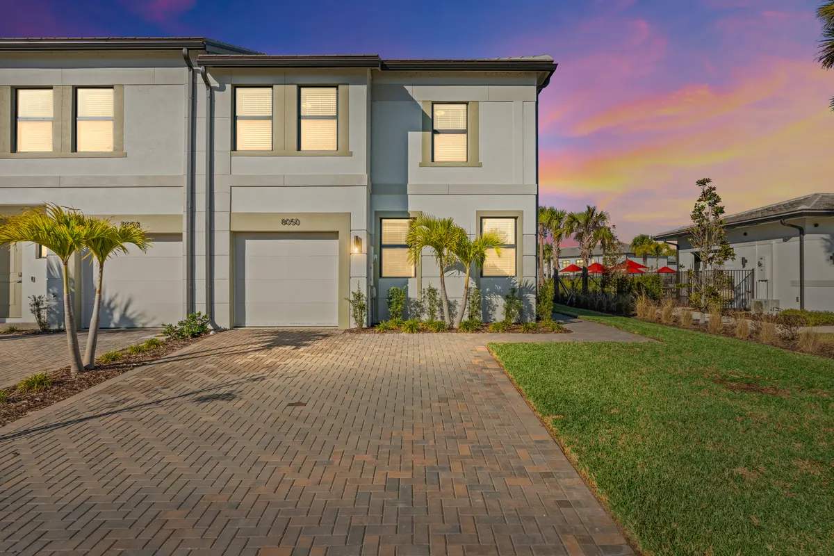 Opal end-unit townhome at dusk with lit windows and a paver drive