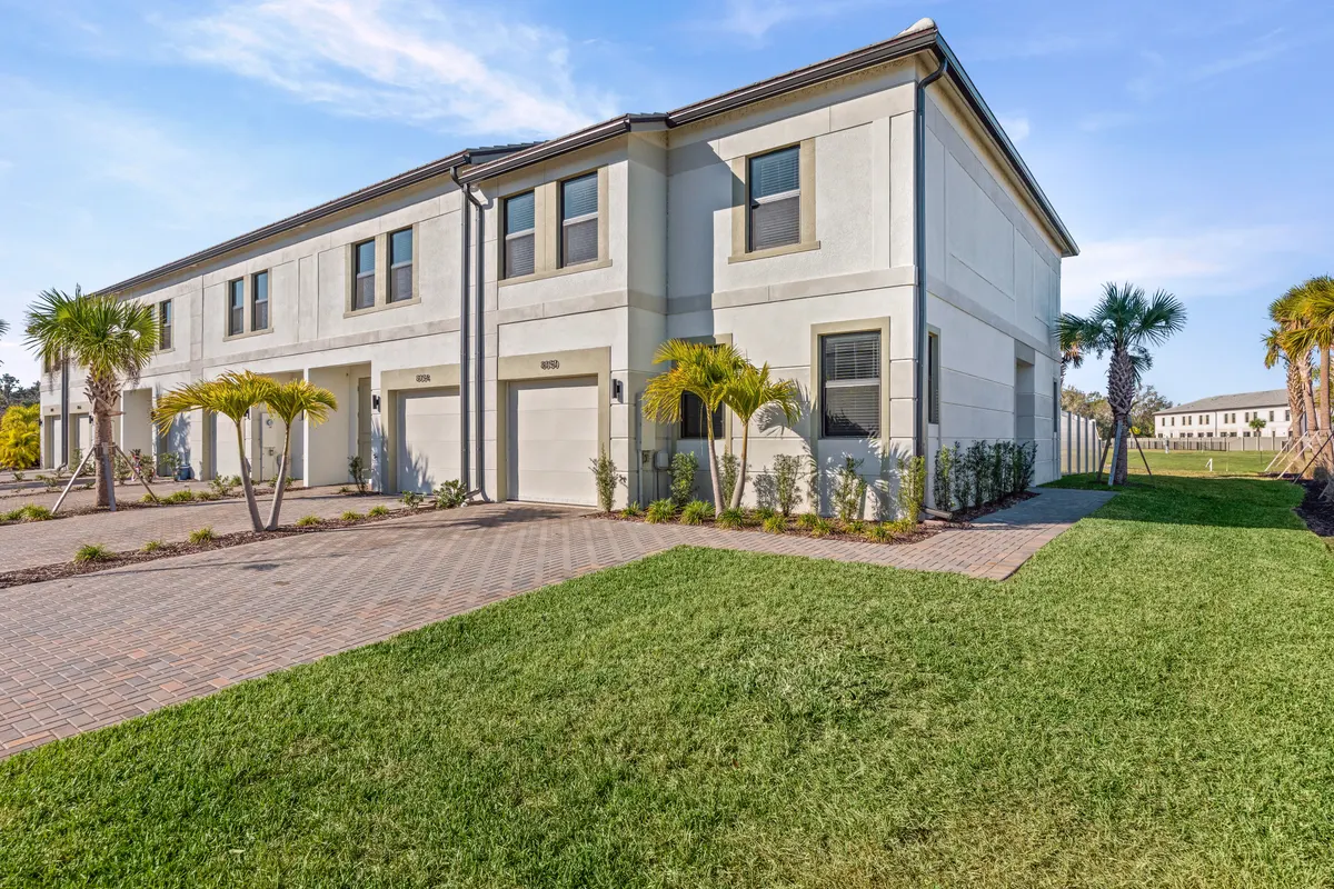 Row of townhomes with single-car garages seen from the lawn