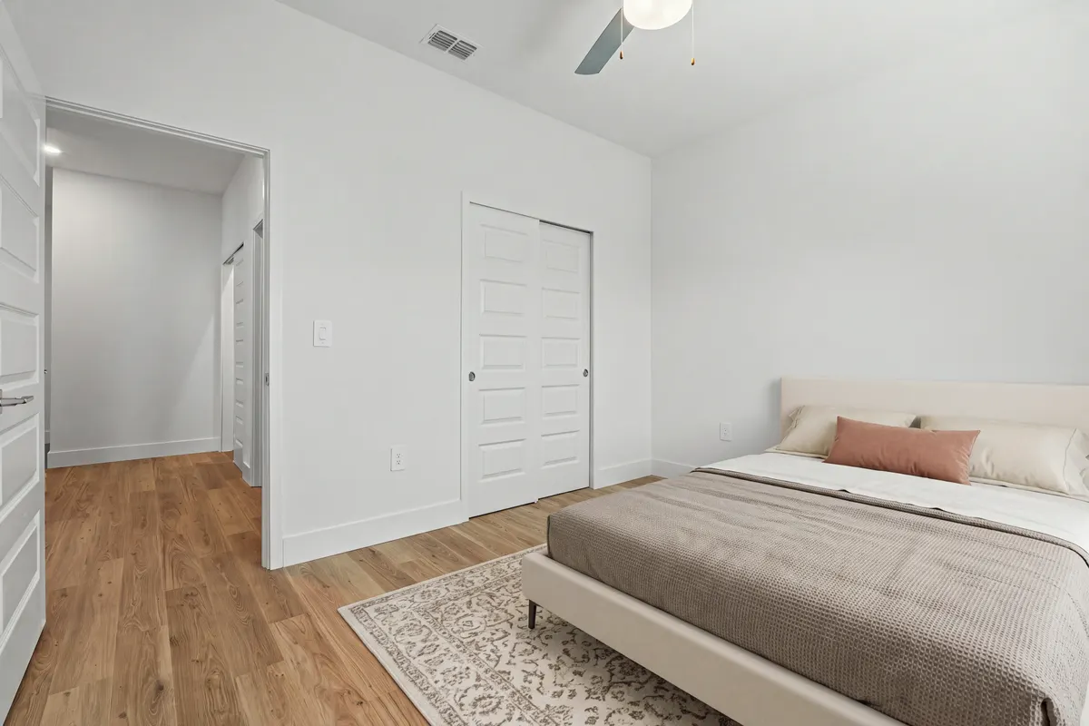 Opal bedroom with a bed and a rug beside a sliding-door closet and a doorway to the hall. Virtually staged.